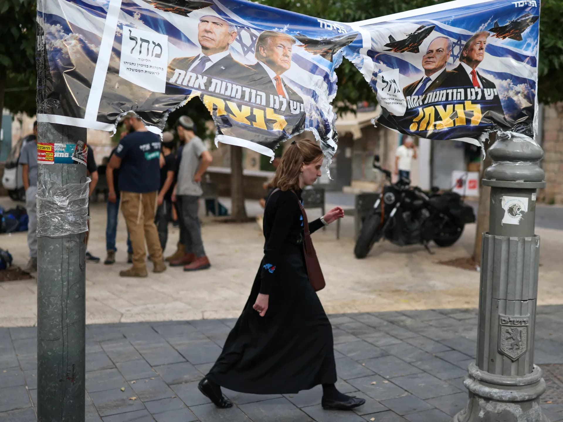 Una mujer camina bajo carteles electorales del Likud con Netanyahu y Trump en Jerusalén