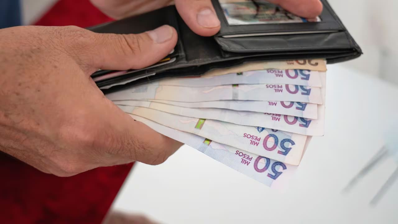 Una persona saca billetes de 50.000 pesos de su billetera