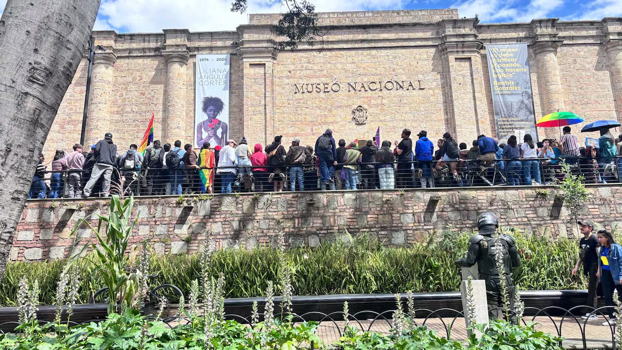 Manifestantes con banderas frente a la fachada del Museo Nacional, en Bogotá, mientras un policía antidisturbios vigila