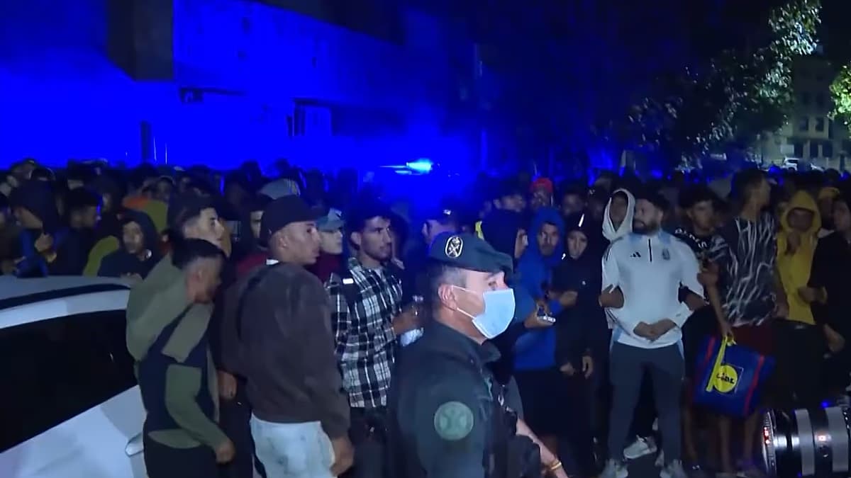 Agentes acompañan a un grupo de migrantes durante el traslado hacia el puerto de Ceuta