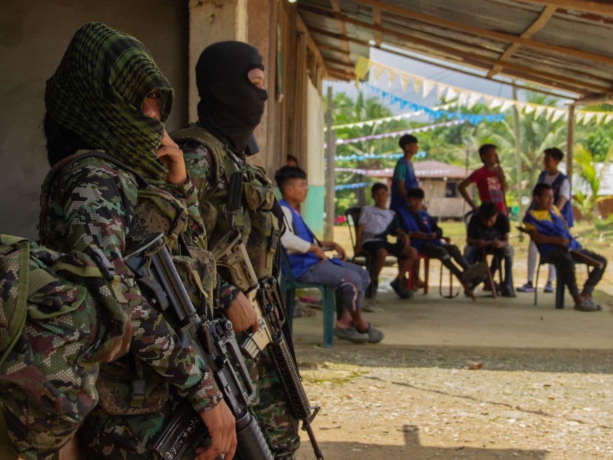 Hombres armados de un grupo ilegal frente a un grupo de jóvenes en una zona rural