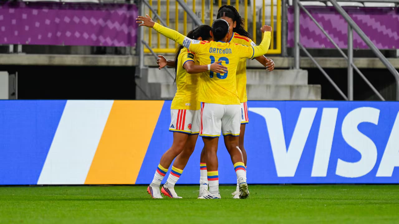 Jugadoras de la selección Colombia sub-20, de camiseta amarilla, se abrazan en la cancha de un estadio