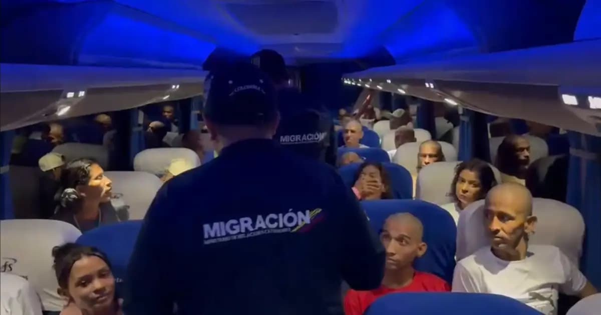 Un funcionario de Migración Colombia habla con extranjeros dentro de un bus durante el traslado