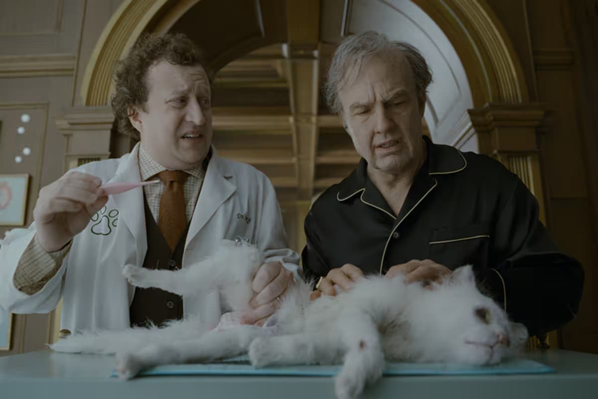 Tom Cruise, caracterizado como el magnate Digger Rockwell, junto a un veterinario y un gato blanco en una escena de la película