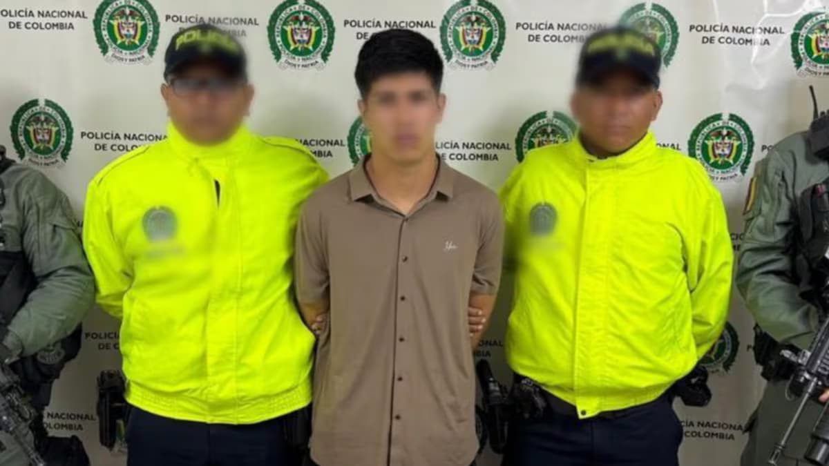 Alias Camilo, custodiado por dos policías tras su captura en Ibagué