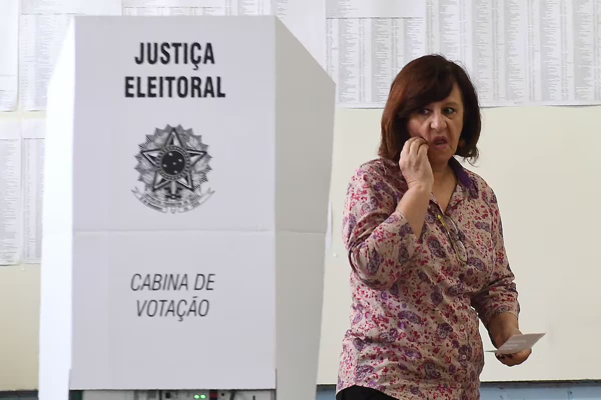 Una votante junto a una cabina de votación de la Justicia Electoral de Brasil