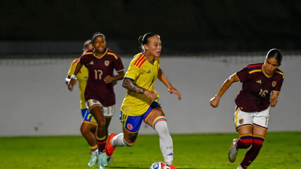 Una jugadora de la selección Colombia conduce el balón ante dos rivales de Venezuela en el amistoso femenino