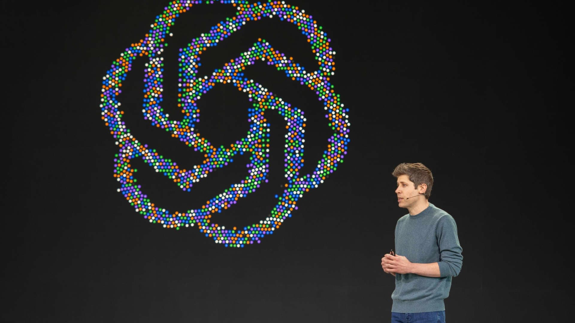 Sam Altman, director ejecutivo de OpenAI, habla en un escenario junto al logo de la compañía