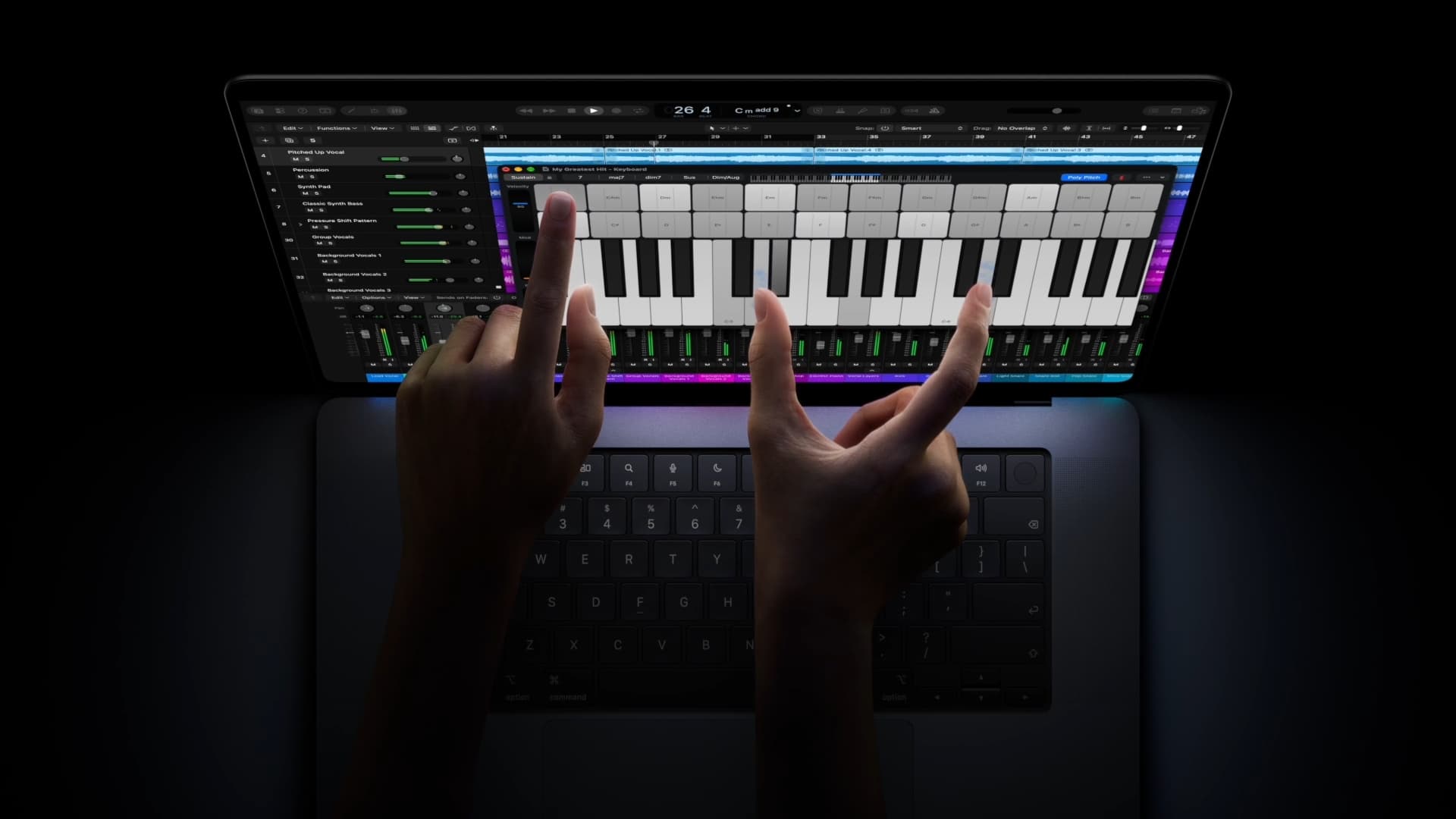 Dos manos tocan la pantalla del nuevo MacBook Pro mientras usan un teclado musical en una aplicación de edición de audio