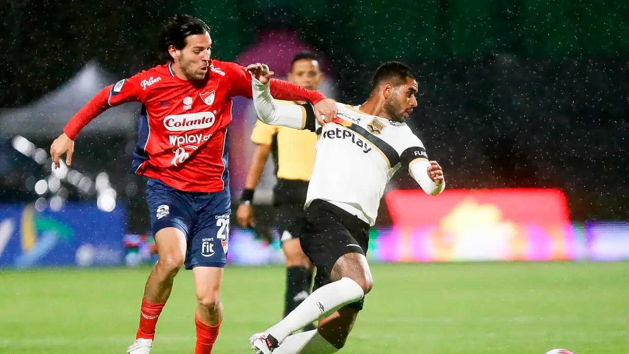 Un jugador del Independiente Medellín disputa el balón con un rival de Internacional de Bogotá bajo la lluvia en el estadio Metropolitano de Techo