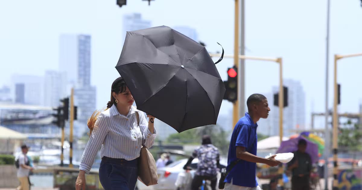 Una mujer se protege del sol con una sombrilla mientras camina por una calle de Cartagena