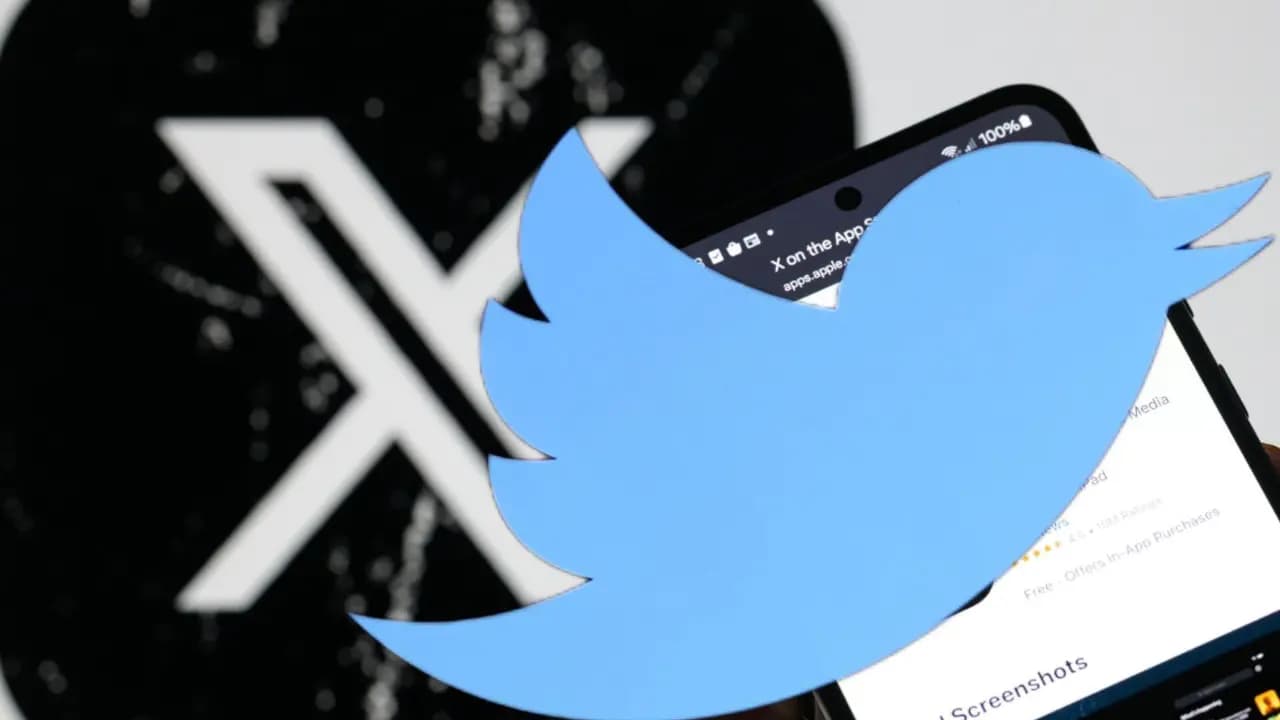 Una silueta recortada del pájaro azul de Twitter sostenida delante de un teléfono móvil, con el logotipo blanco de X impreso sobre un fondo negro al costado