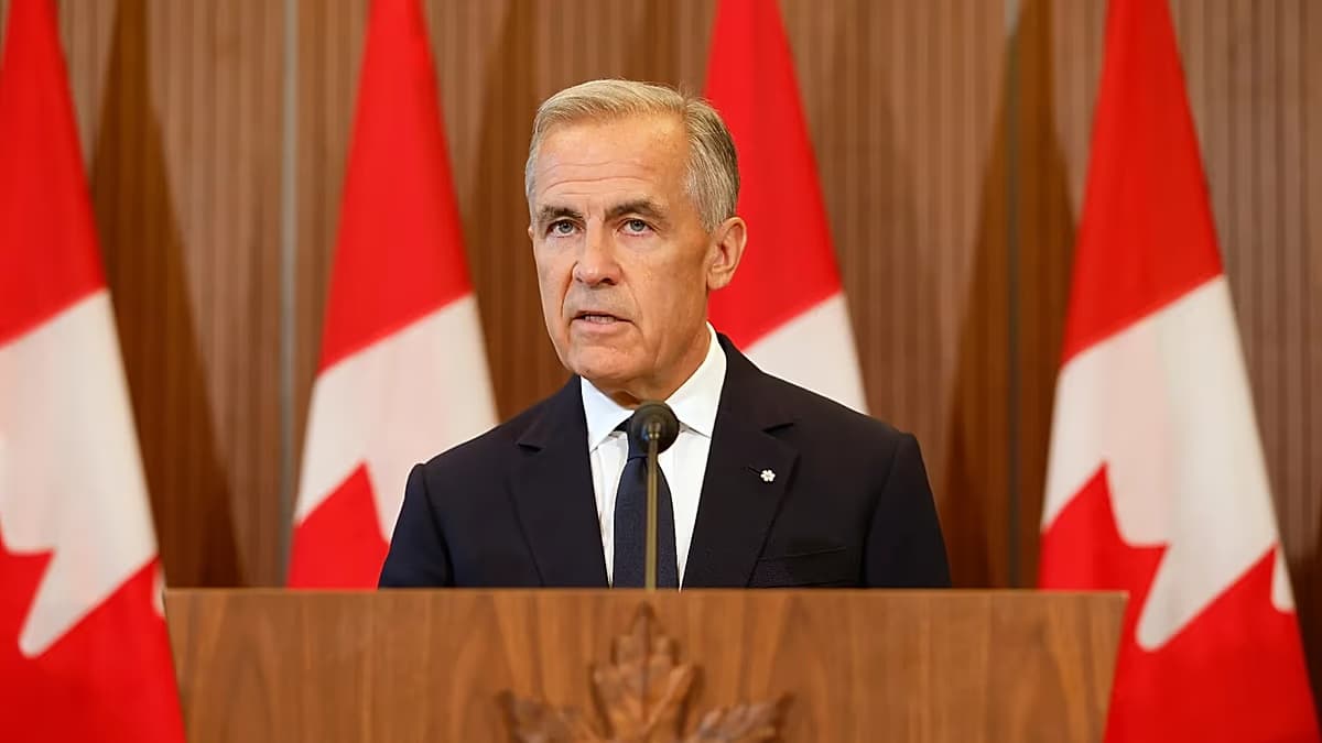 El primer ministro canadiense Mark Carney habla en un atril frente a varias banderas de Canadá