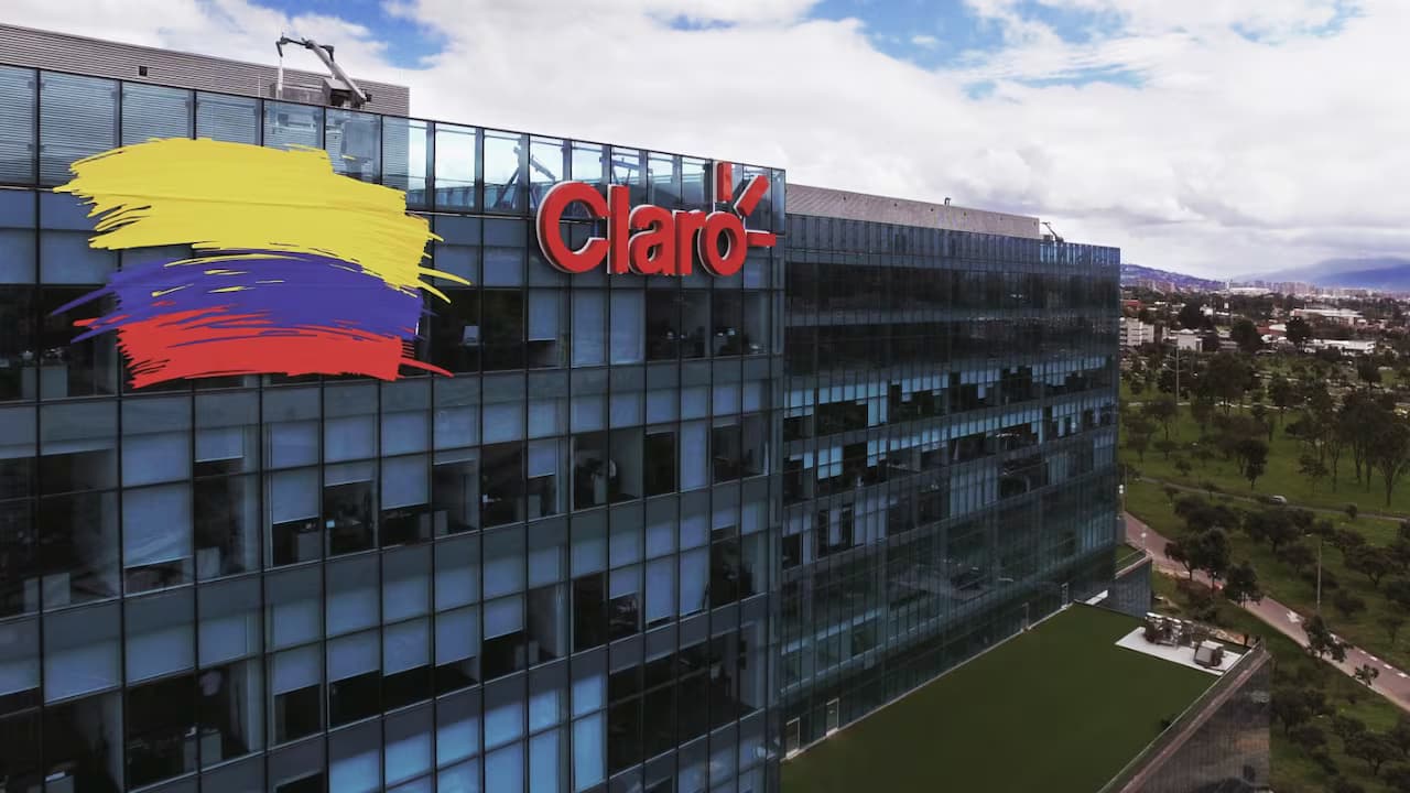Trabajos de tendido de fibra óptica sobre postes de red en una calle colombiana