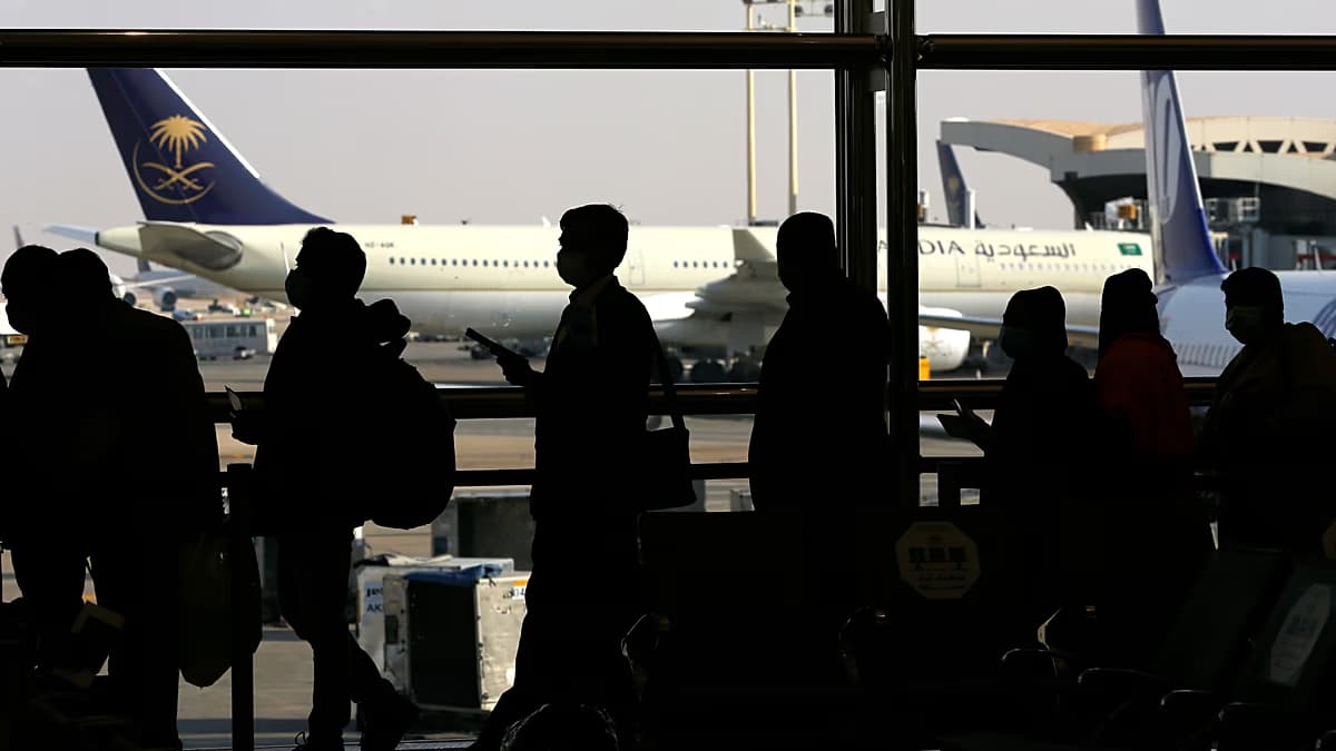 Pasajeros en la terminal del aeropuerto internacional Rey Jalid de Riad, con aviones de Saudia al fondo