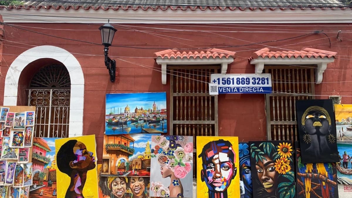 Calle del barrio Getsemaní, en Cartagena, con fachadas de colores y vecinos en la puerta