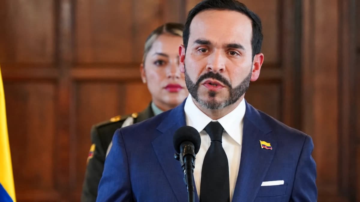 El presidente Abelardo De La Espriella habla ante un micrófono de pie, con la bandera de Colombia a un costado y una oficial de policía uniformada detrás