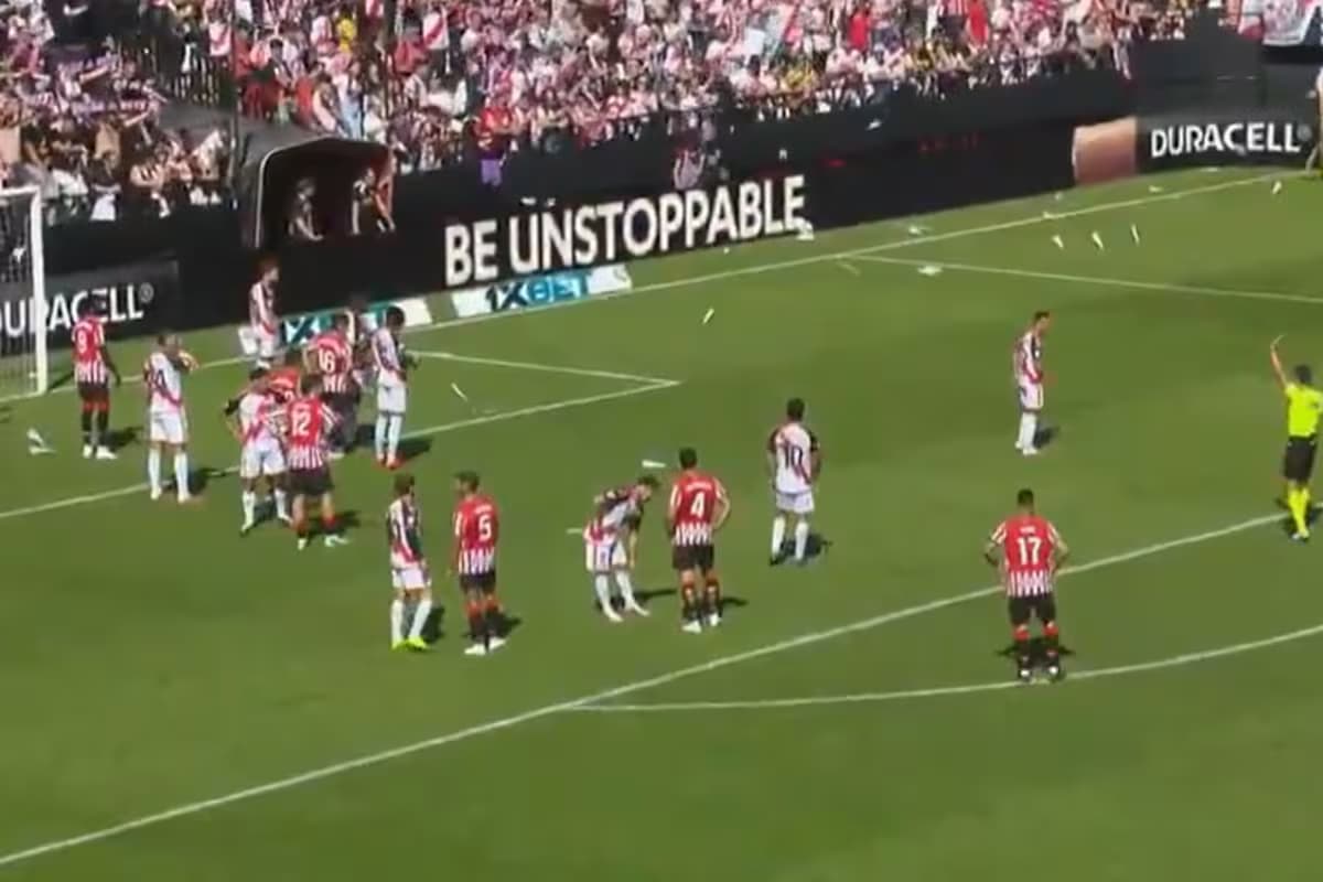 Jugadores del Rayo Vallecano y del Athletic esperan sobre un césped salpicado de avioncitos de papel en Vallecas