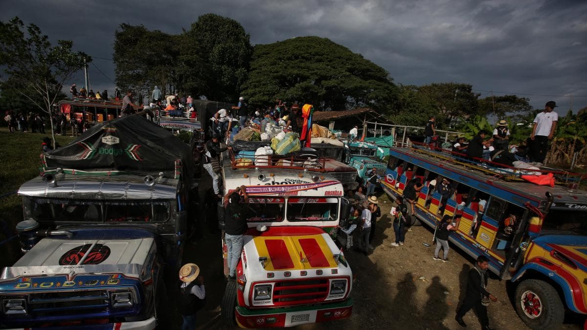 Comuneros indígenas reunidos junto a varias chivas bajo un cielo encapotado en el norte del Cauca