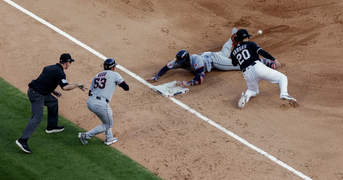 Un corredor de Cleveland se desliza de cabeza hacia la tercera base ante un jugador de los White Sox