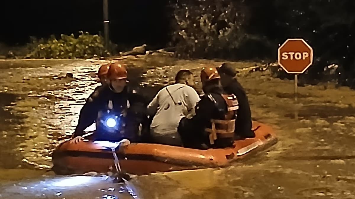 Rescatistas trasladan en una lancha neumática a varias personas por una calle inundada durante la noche en Cataluña