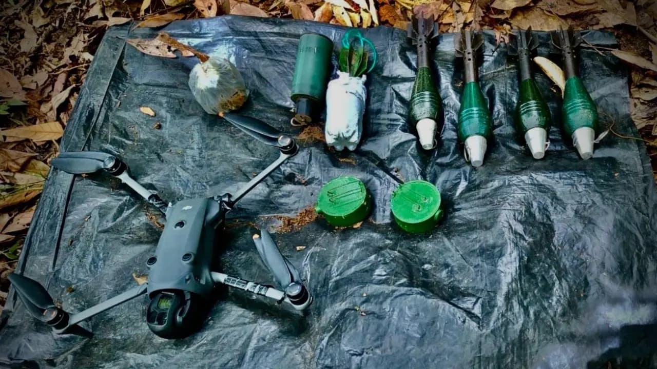 Un dron y varias cargas explosivas de fabricación artesanal dispuestos sobre una lona negra en medio del monte