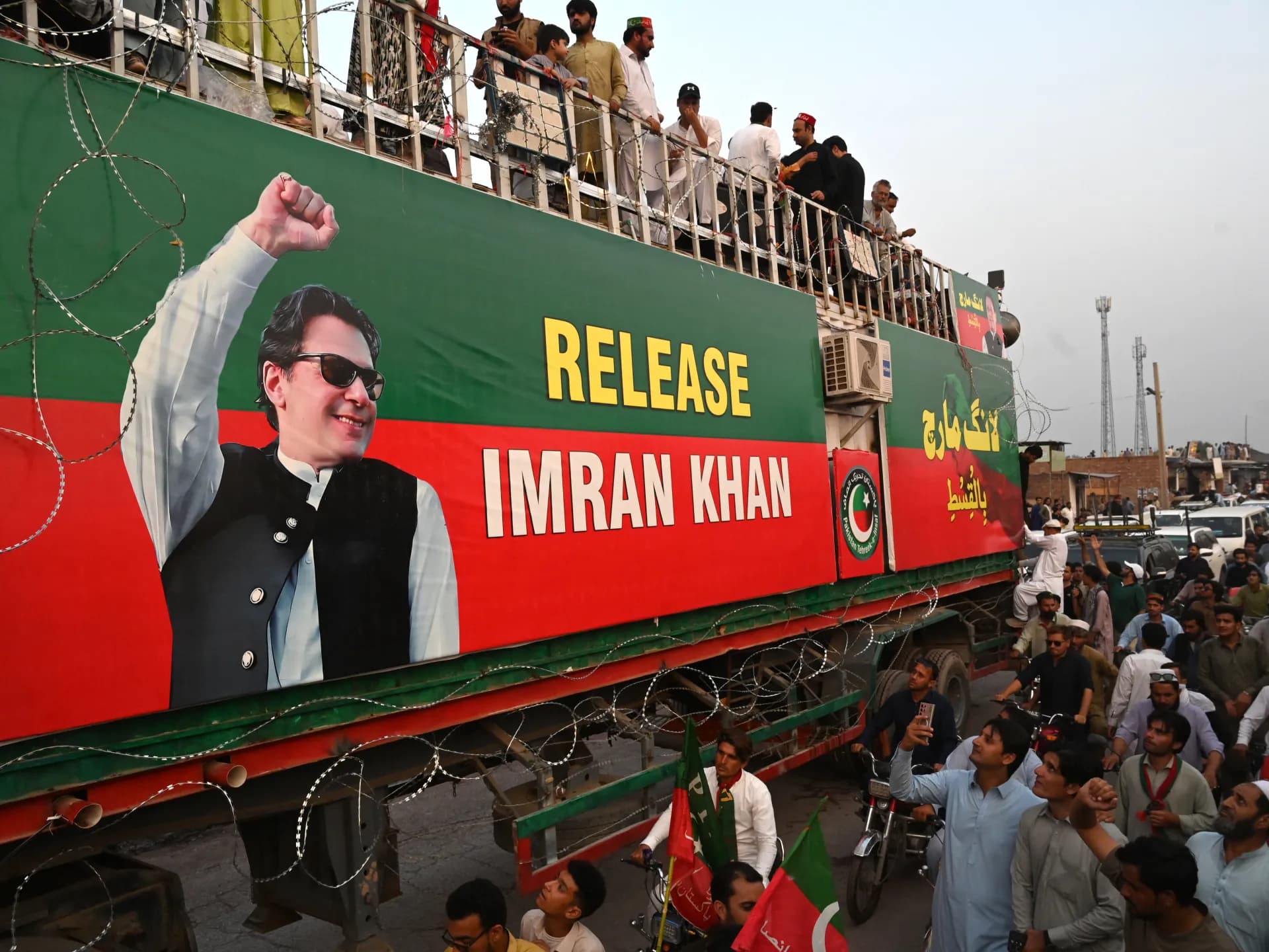 Simpatizantes del PTI rodean un camión con un cartel que pide la liberación de Imran Khan durante la marcha