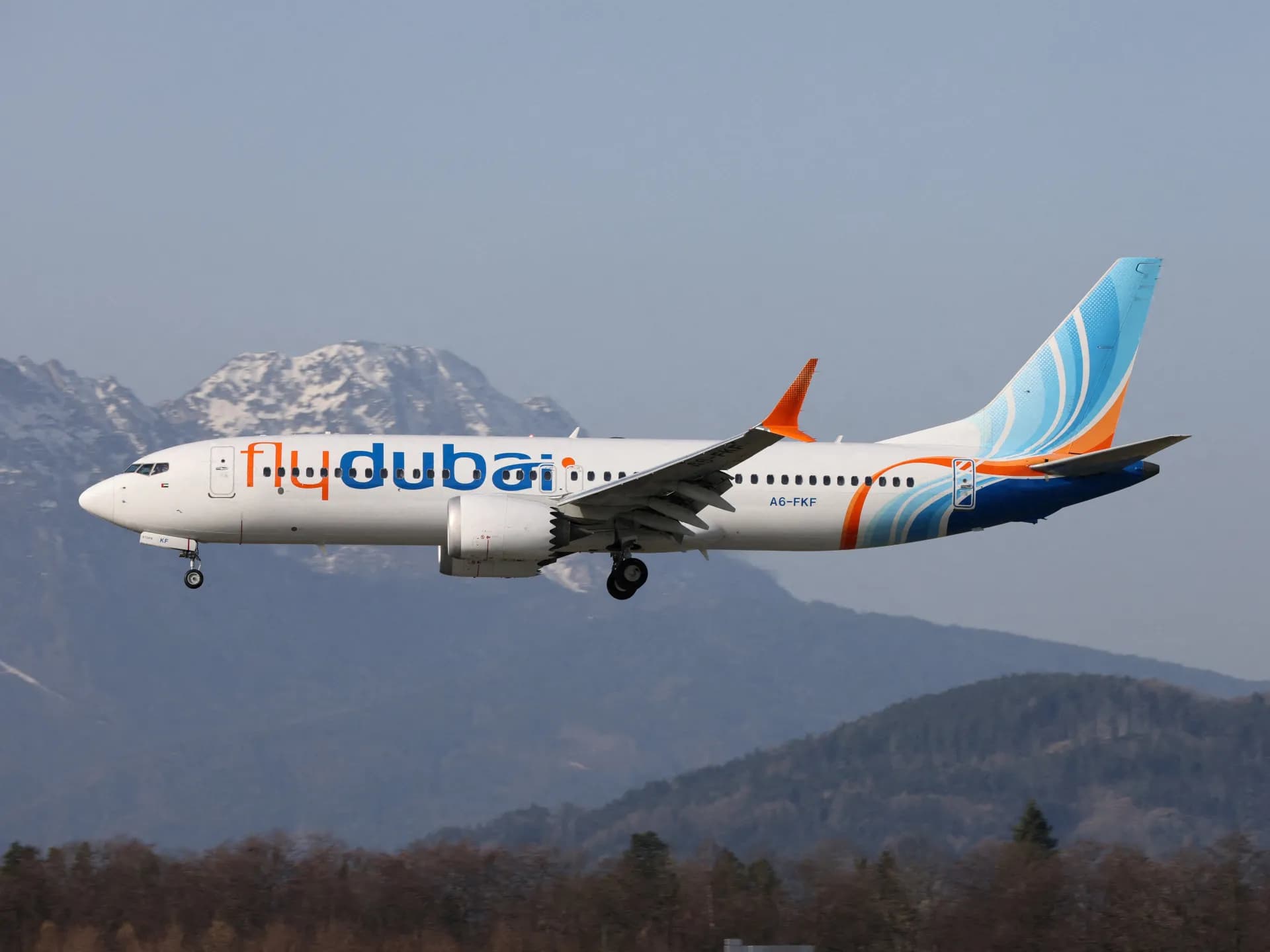 Un Boeing 737 de Flydubai en vuelo con montañas nevadas al fondo