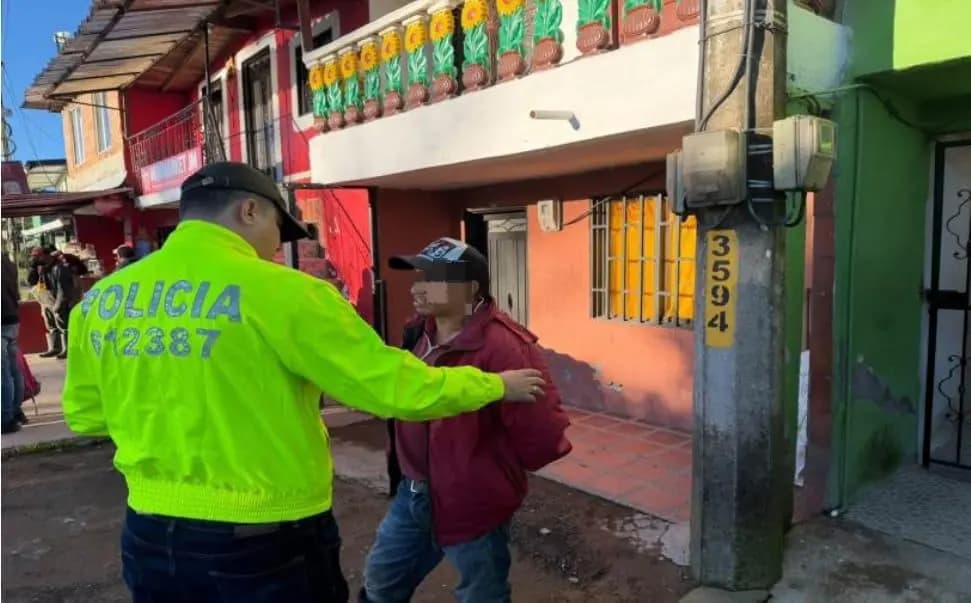 Un policía conduce al capturado, con el rostro difuminado, en una calle de Santa Rosa de Osos