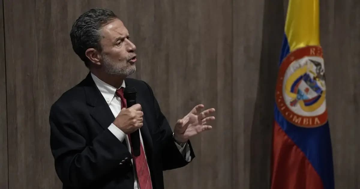 El canciller de Colombia, Omar Bula, habla con un micrófono junto a la bandera de Colombia