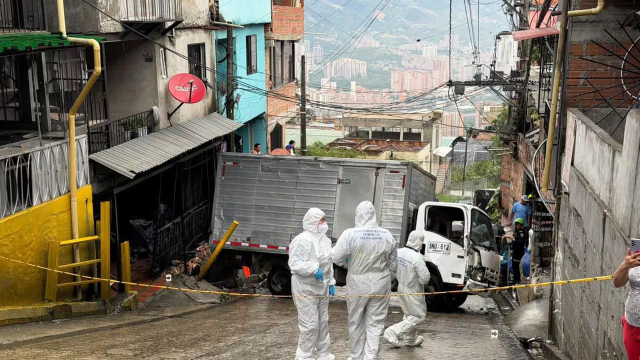 Agentes de la Policía Judicial de la Secretaría de Movilidad junto al camión accidentado en una calle empinada de Santo Domingo Savio, en Medellín