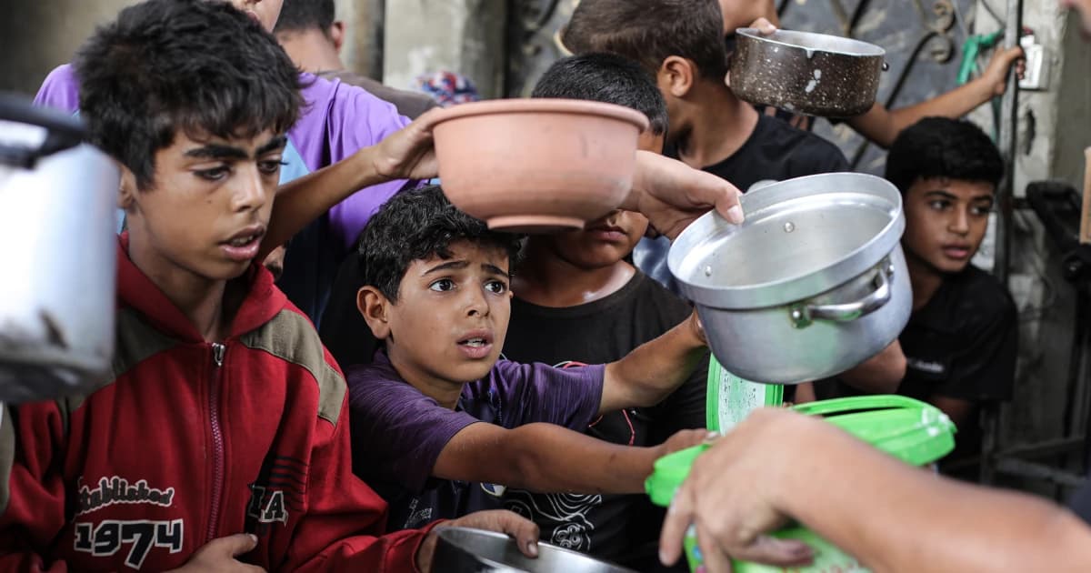 Niños palestinos con ollas esperan una ración de comida en Gaza