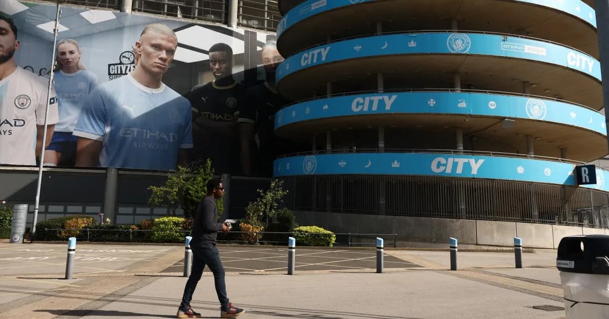 Un hombre camina frente al estadio Etihad, sede del Manchester City
