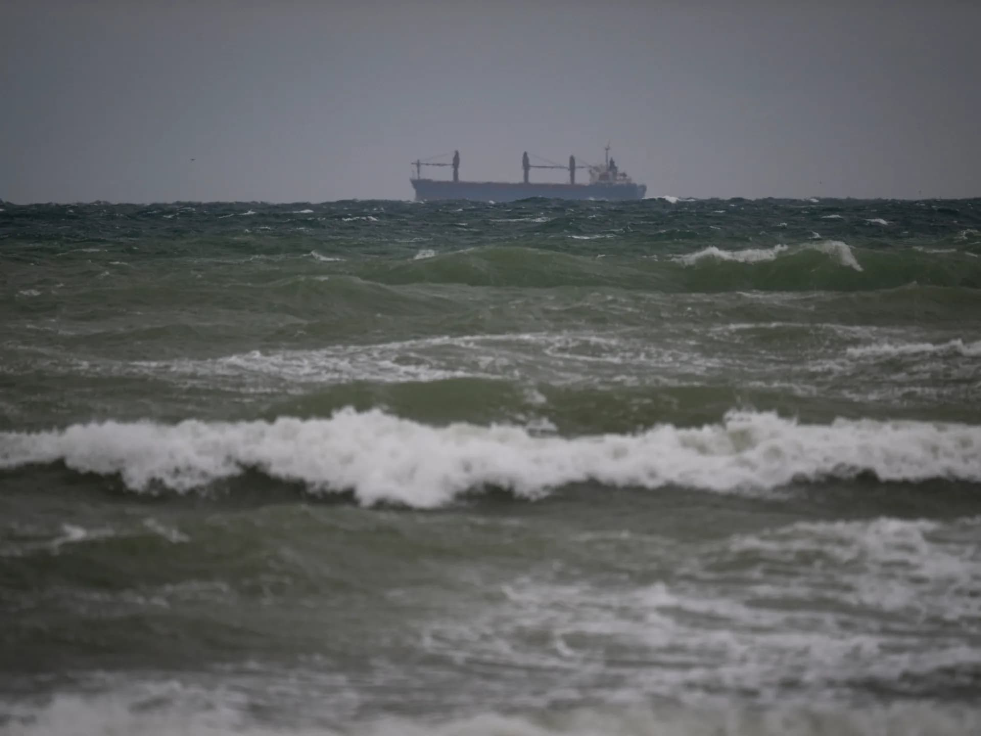 Un buque de carga navega en el horizonte sobre un mar Negro agitado y gris
