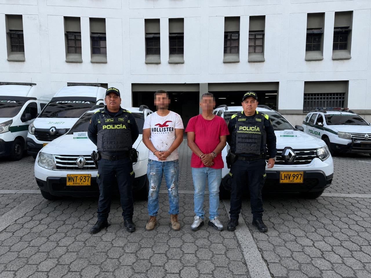 Policías junto a dos capturados frente a camionetas de la Policía