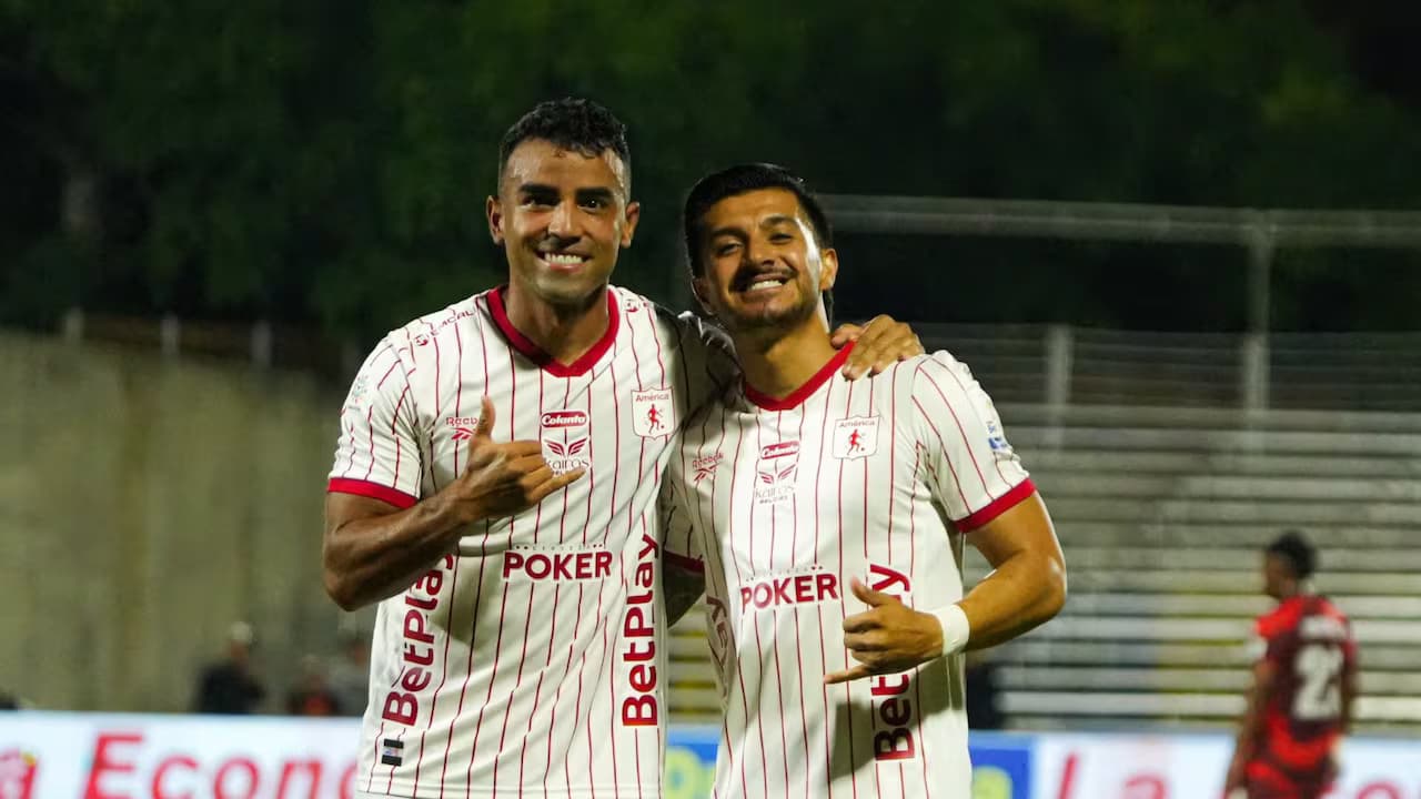 Dos jugadores del América de Cali celebran sonrientes durante el partido ante Barranquilla FC en el estadio Romelio Martínez