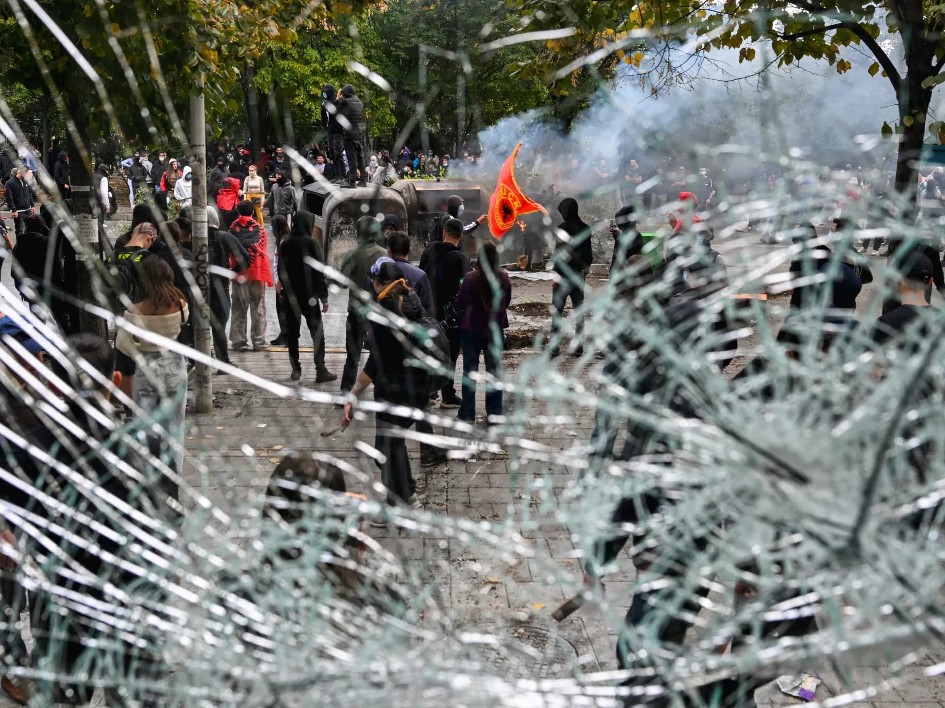 Manifestantes y gases lacrimógenos en Tirana, vistos a través de un vidrio roto