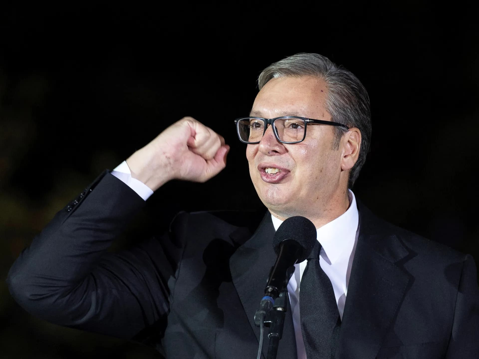 Aleksandar Vučić, con el puño en alto, habla frente a un micrófono durante un acto nocturno en Belgrado