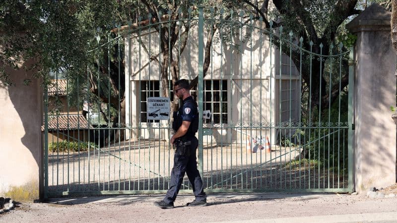 Un policía camina frente a la verja cerrada de un museo rodeado de olivos