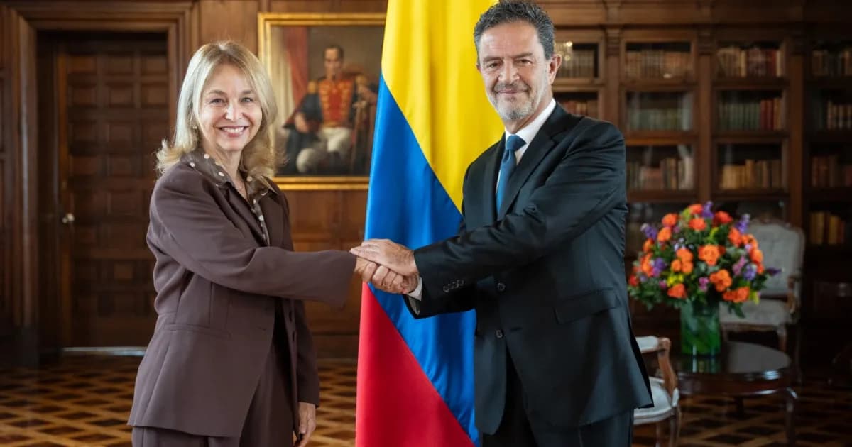 Tania Gilinski y el canciller Omar Bula se dan la mano junto a la bandera de Colombia en el Palacio de San Carlos