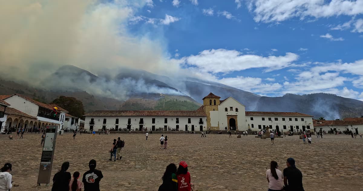 La Plaza Mayor de Villa de Leyva con el cerro en llamas y una columna de humo al fondo