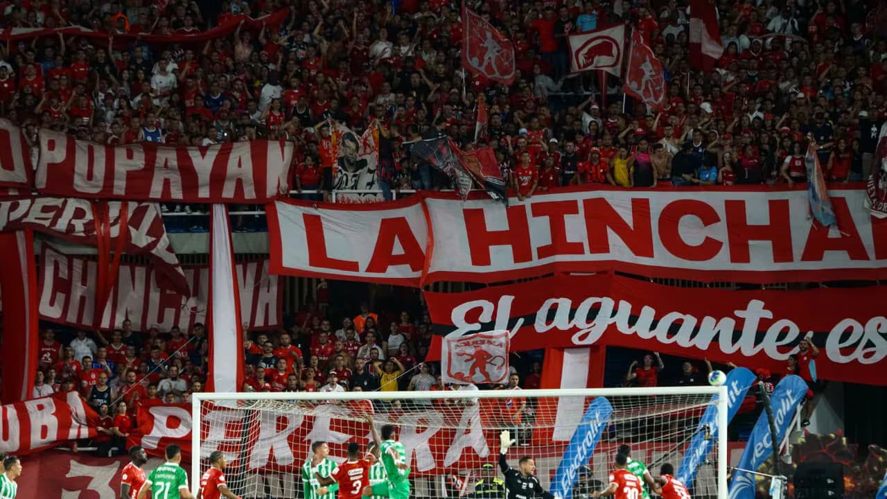 Jugadores de Atlético Nacional y América de Cali disputan el balón en un clásico del fútbol colombiano