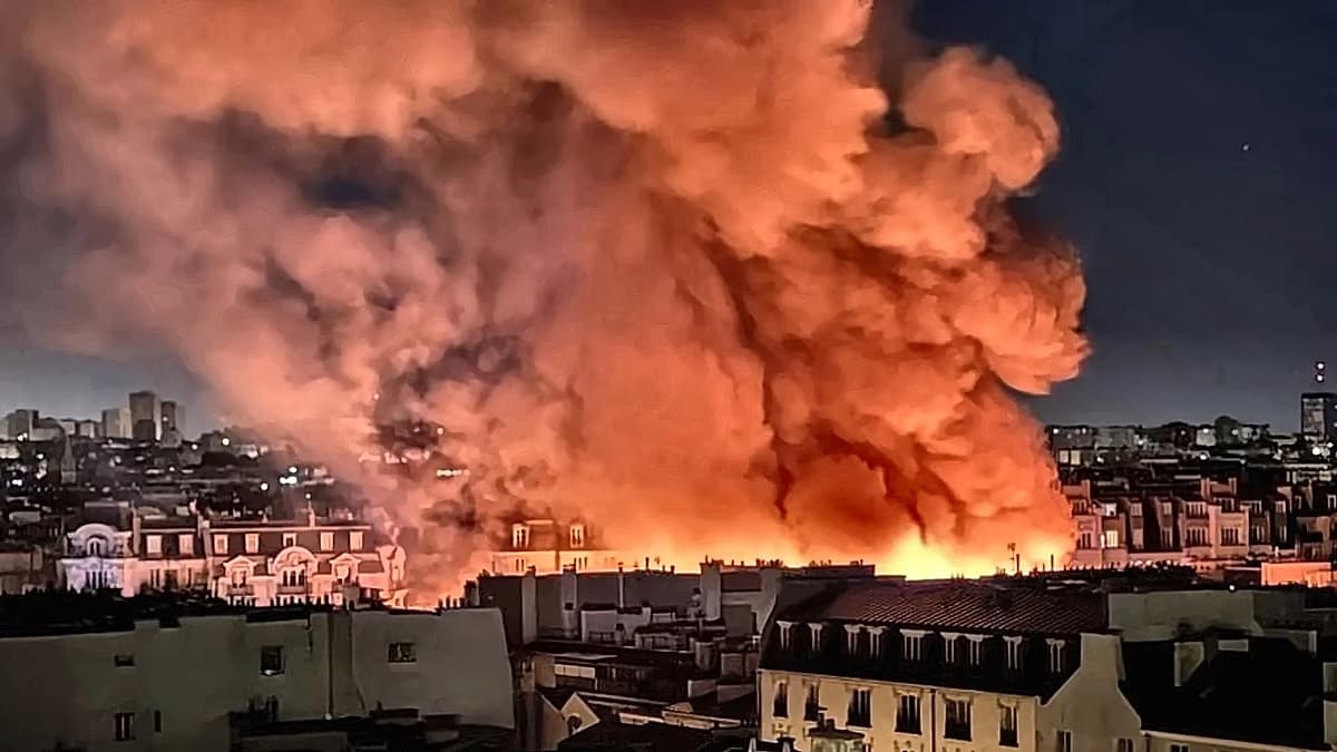 Una gran columna de humo anaranjado se eleva sobre los tejados de París durante el incendio nocturno del mercado