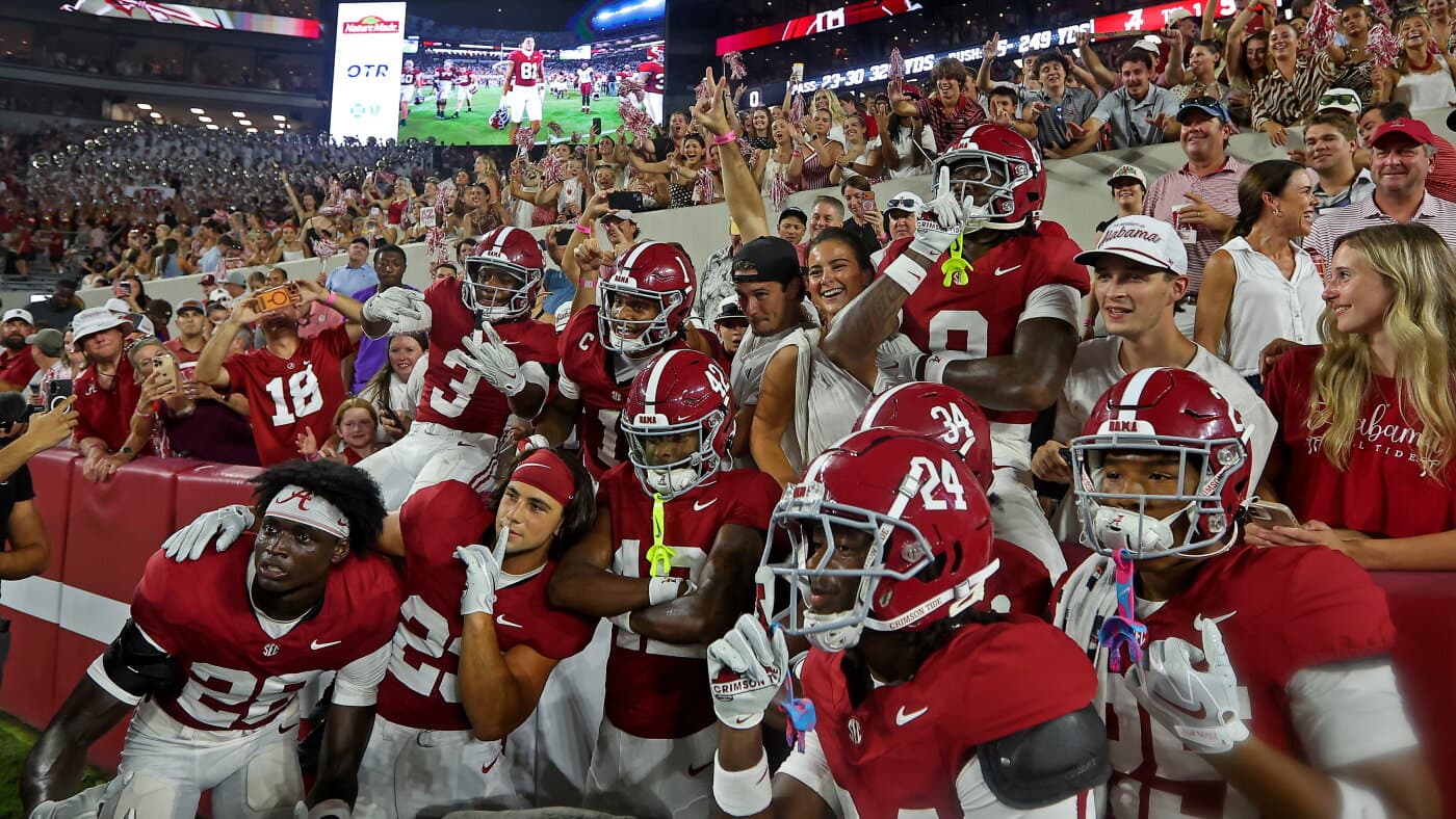 Jugadores de fútbol americano de Alabama posan con aficionados en las graderías tras un partido en Tuscaloosa