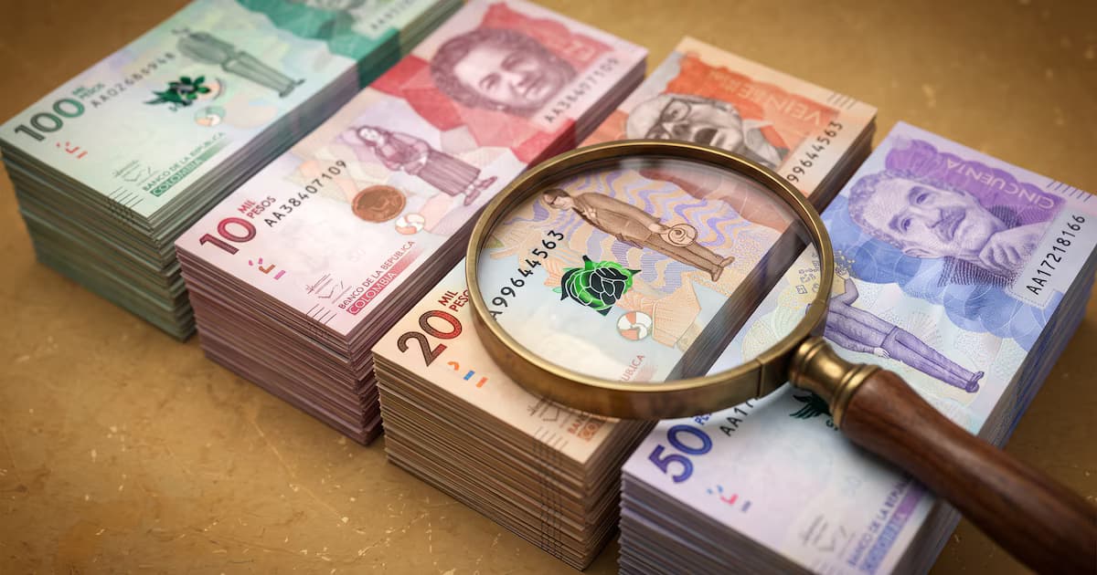 Fajos de billetes colombianos bajo una lupa