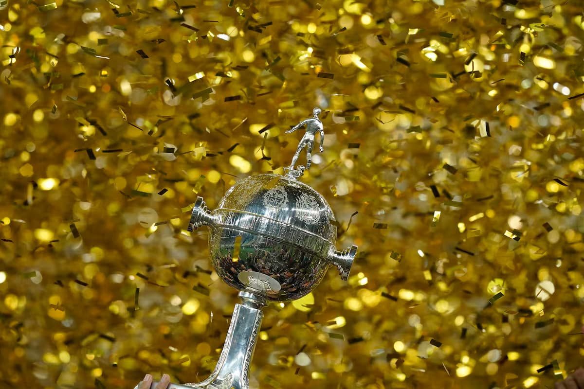El trofeo de la Copa Libertadores entre papel picado dorado