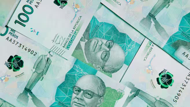 Varios billetes colombianos de cien mil pesos extendidos unos sobre otros vistos de cerca