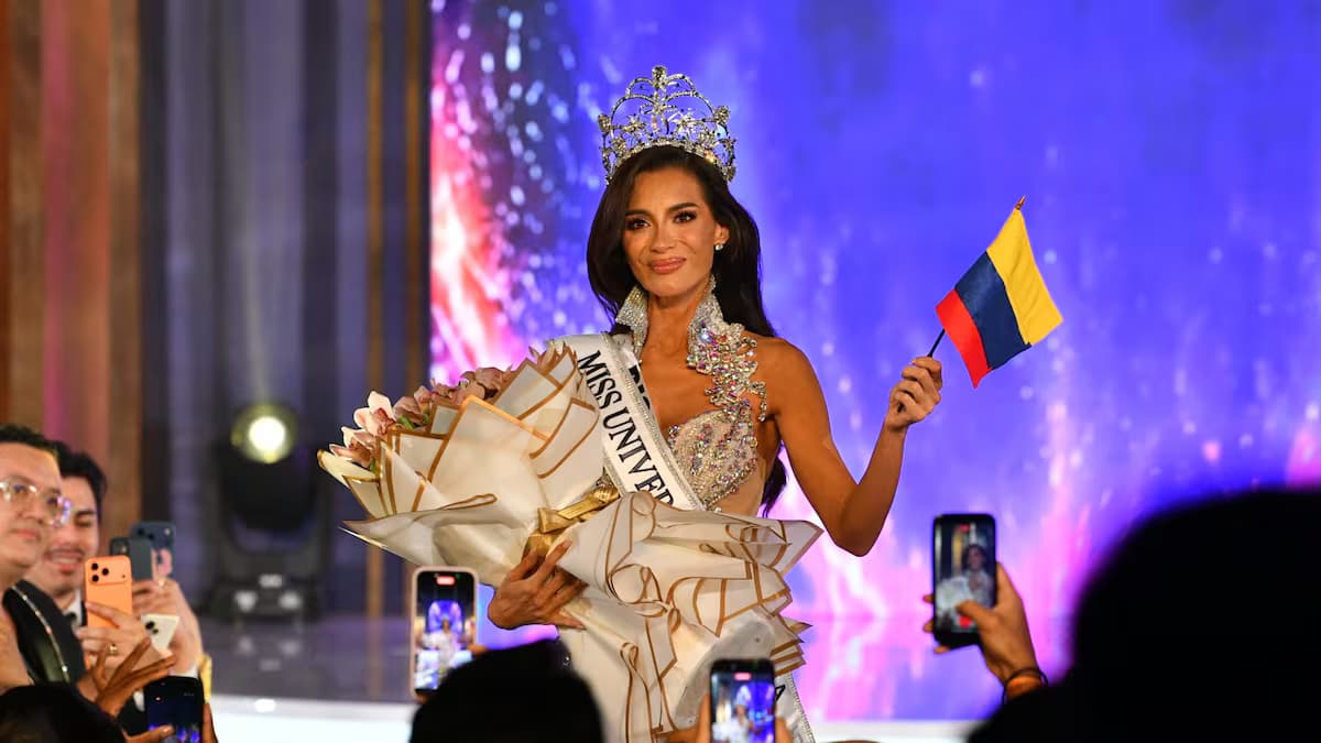 María Alejandra López, con la corona y la banda de Miss Universe Colombia, ondea una bandera de Colombia en el escenario