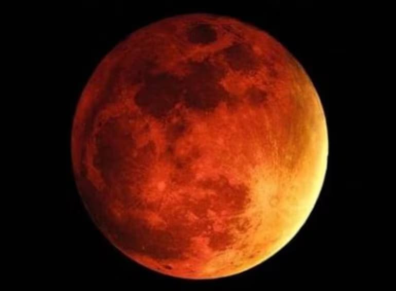 La Luna llena teñida de rojo cobrizo sobre un cielo completamente negro durante un eclipse