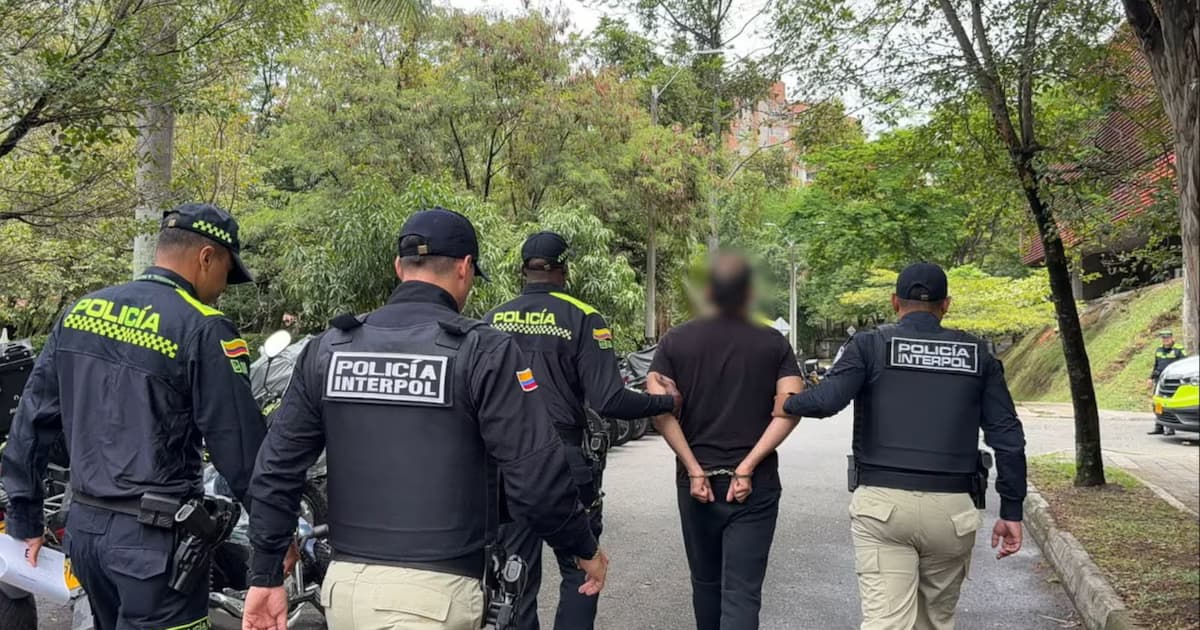 Agentes de la Policía y de Interpol conducen esposado a alias Ash tras su retención en Antioquia